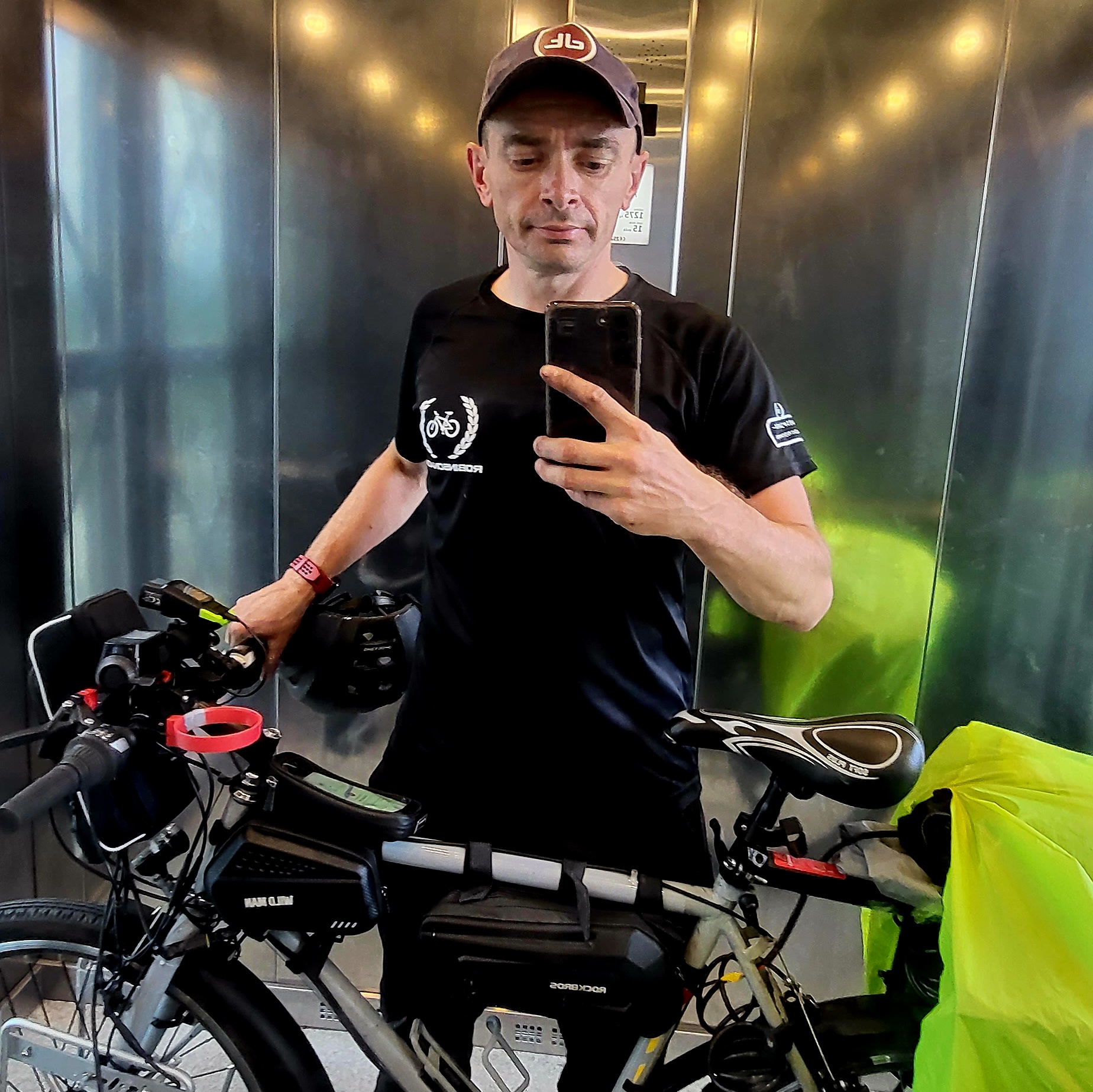 Selfie w windzie z rowerem turystycznym, które uchwyca moment przed kolejnym etapem podróży, podkreślając determinację i zamiłowanie do wypraw rowerowych.