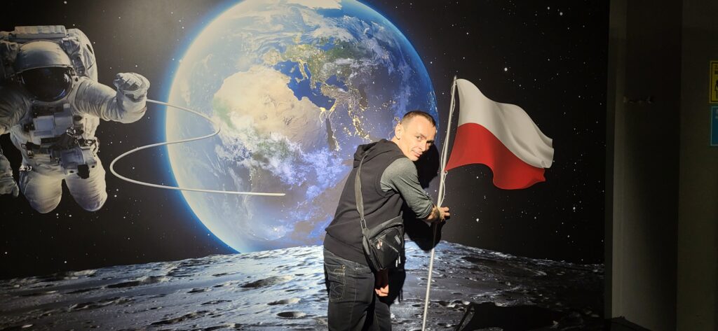 
Na tle księżycowego pejzażu i kosmicznego widoku Ziemi, z dumą symbolizuję swoje ambicje i pasję do odkrywania, trzymając polską flagę – obraz aspiracji sięgających gwiazd.