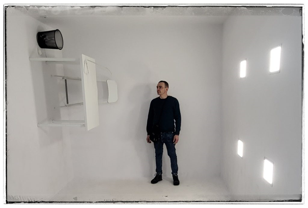 Niecodzienne ujęcie w jasnym pomieszczeniu z nietypowo zamocowanymi meblami – scena, która odzwierciedla kreatywność i wyjątkowe elementy mojego Dossier artystycznego.