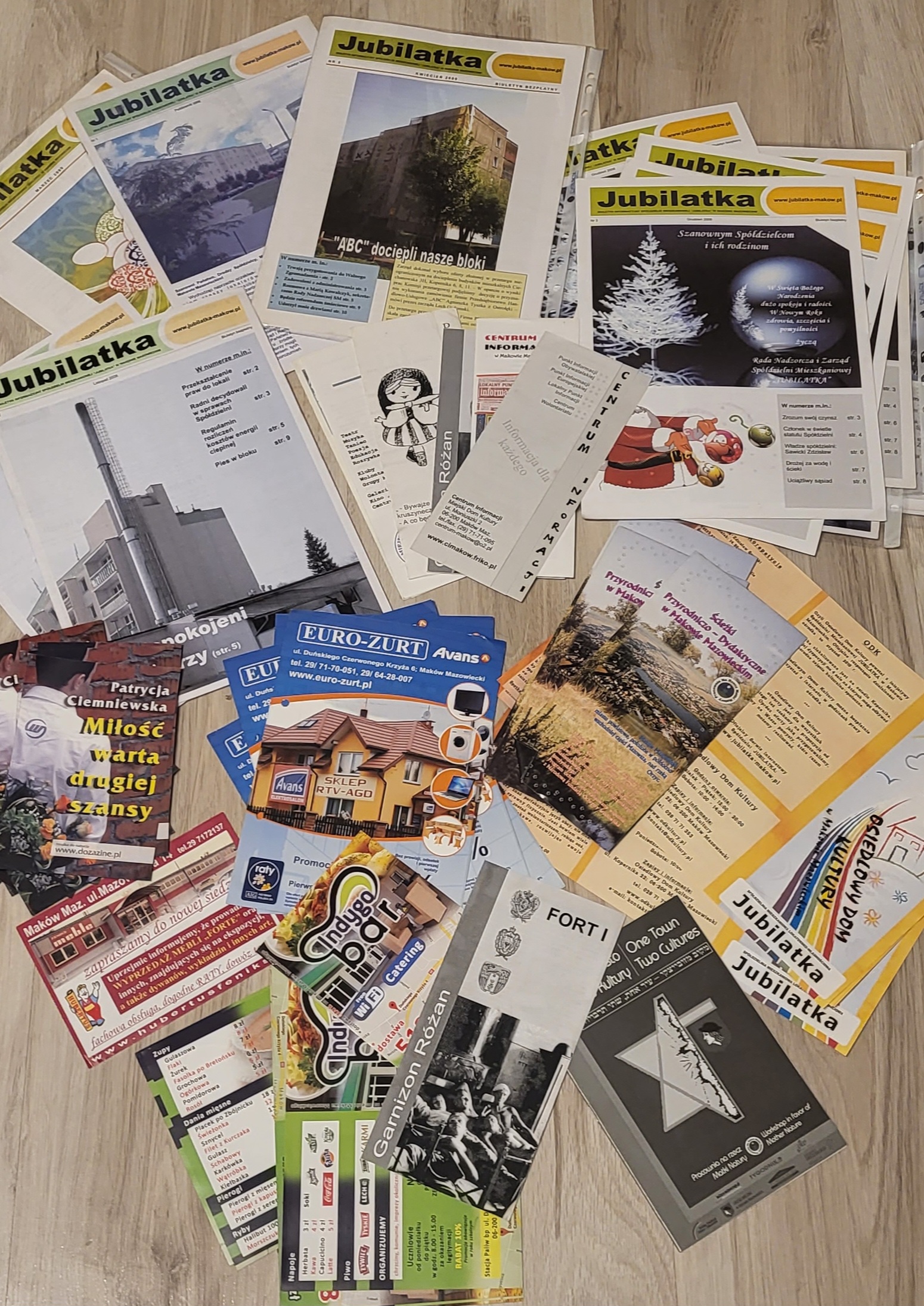 Kolekcja biuletynów, ulotek i materiałów promocyjnych, w tym wydawnictwa „Jubilatka”, prezentujące różnorodne projekty graficzne i publikacje, które łączyły lokalne inicjatywy z kreatywnym designem.